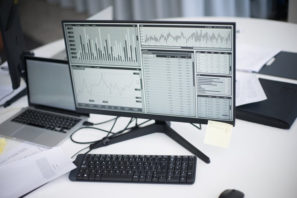 pexels photo 8636589 A professional workspace featuring computers and analytical graphs on a monitor, symbolizing modern business environment.